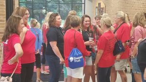 Teachers gather smiling and talking before All Staff Kickoff