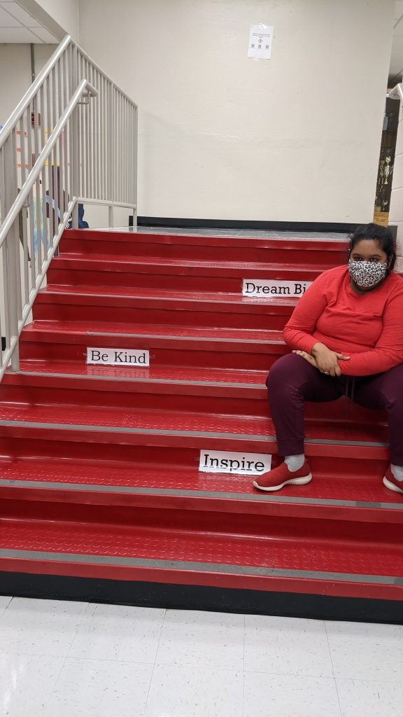 Student sitting on stairs with insprational signs